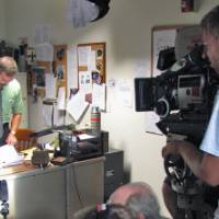 The summer film crew pointing a camera at an actor in a fake office